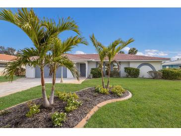 House exterior featuring a landscaped lawn, palm trees, and a paved driveway at 468 Leger Dr, Nokomis, FL 34275