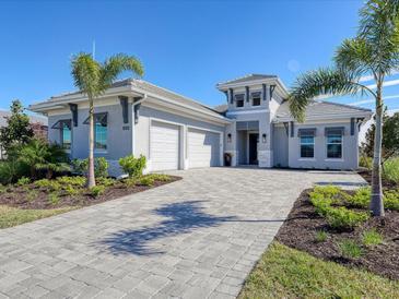 Two-story home with gray exterior, three-car garage, and paver driveway at 8372 Sea Glass Ct, Sarasota, FL 34240