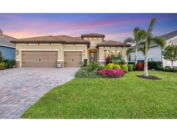 Tan two-story house with two-car garage, landscaping, and palm trees at 13325 Indigo Way, Bradenton, FL 34211