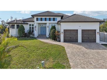 Two-story home with light-colored siding, a three-car garage, and a landscaped yard at 609 Colonial Bay Dr, Nokomis, FL 34275