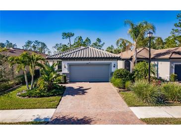 One-story house with gray garage door and a brick driveway, surrounded by landscaping and other homes at 2479 Brassica Dr, North Port, FL 34289