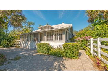Charming bungalow with white exterior, lush landscaping, and a brick driveway at 2525 Ashton Rd, Sarasota, FL 34231