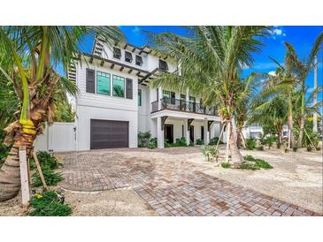 Two-story home with white siding, dark trim, and a brick driveway at 6506 Gulf Dr, Holmes Beach, FL 34217