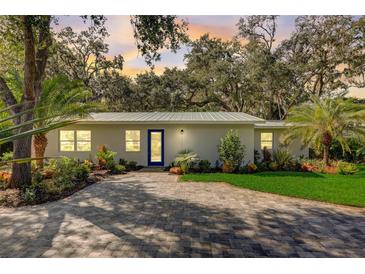 Newly renovated home with a metal roof, paved driveway, and landscaped yard at 730 40Th St, Sarasota, FL 34234