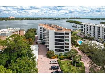Aerial view of waterfront condo building with pool and parking at 8701 Midnight Pass Rd # 106A, Sarasota, FL 34242