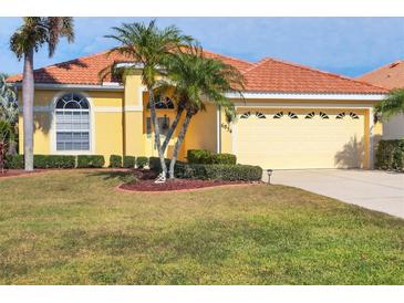 Beautiful yellow house with a tile roof, palm trees, and a landscaped lawn at 6854 Wagon Wheel Cir, Sarasota, FL 34243