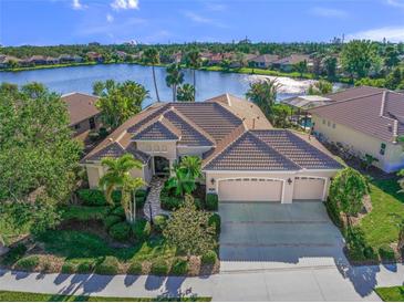 Luxury home with lake view, two-car garage, and lush landscaping at 518 Luminary Blvd, Osprey, FL 34229