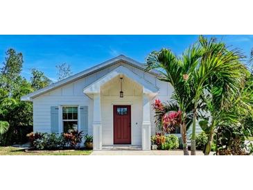 White house with red door, landscaping, and palm trees at 606 19Th W Ave, Palmetto, FL 34221
