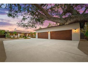 Three-car garage and house exterior at dusk at 4817 Ocean Blvd, Sarasota, FL 34242