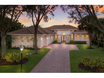 Luxury home with brick driveway, three-car garage, and landscaped yard at 3769 Caledonia Ln, Sarasota, FL 34240