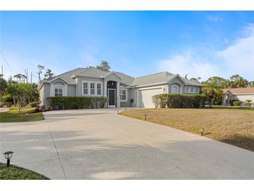 Charming single-story home featuring a concrete driveway and manicured shrubbery against a blue sky at 4801 Brickell Dr, North Port, FL 34286