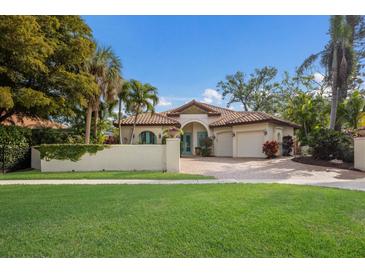 Elegant single-story home with a clay tile roof, turquoise doors, a lush lawn, and a two-car garage at 4946 Brywill Cir, Sarasota, FL 34234