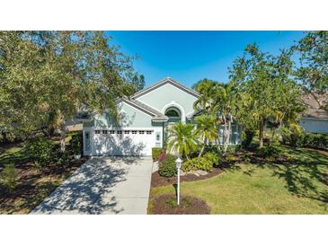 Beautiful light green house with white garage door and lush landscaping at 6523 Virginia Xing, University Park, FL 34201