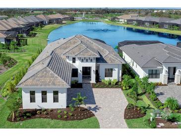 Luxury home with lake view, paver driveway, and landscaped yard at 8367 Sea Glass Ct, Sarasota, FL 34240