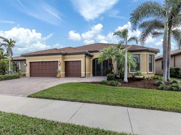 Tan two-story house with brown garage doors and lush landscaping, two palm trees in front at 19696 Petrino St, Venice, FL 34293