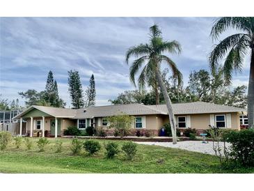 Single-story house with a landscaped yard, palm trees, and a light beige exterior at 2426 Nassau St, Sarasota, FL 34231