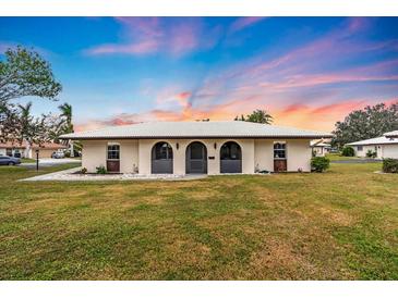 Tan single story home with a gently sloping lawn at 430 Botticelli Dr # 430, Nokomis, FL 34275