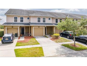 Tan townhouses with attached garages and landscaped yards at 5809 Leopardstown Dr, Tampa, FL 33610