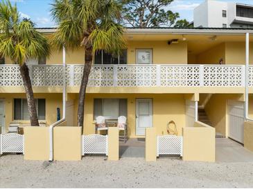 Two-story yellow condo building with balconies, palm trees, and white lattice fencing at 5955 Midnight Pass Rd # 4E, Sarasota, FL 34242