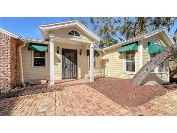 Cute yellow house with a charming front porch and brick walkway at 8440 Midnight Pass Rd, Sarasota, FL 34242