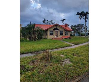 Tan house with red roof, palm trees, and a grassy yard at 2502 Riverside E Dr, Bradenton, FL 34208