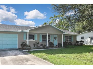 Tan house with light blue accents, a double garage door, and a manicured lawn at 3111 Taunton W Dr, Bradenton, FL 34205
