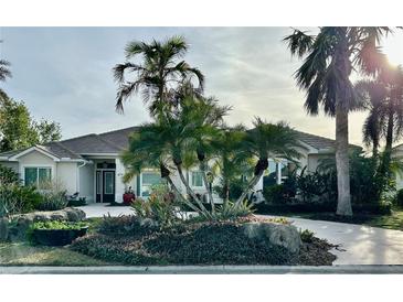 Single-story home with tile roof, palm trees, and landscaped yard at 479 Summerfield Way, Venice, FL 34292