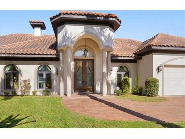 Inviting home exterior with tile roof, arched entryway, and manicured lawn at 4937 Oxford Dr, Siesta Key, FL 34242