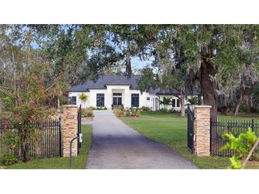 White two-story house with gated entry, manicured lawn, and mature trees at 15125 Waterline Rd, Bradenton, FL 34212
