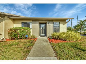 Front view of a light beige house with gray accents, landscaped lawn, and walkway at 2709 60Th Avenue N Plz # D, Bradenton, FL 34207