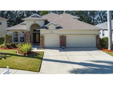 House exterior featuring a three-car garage, stone accents, and lush landscaping at 3439 101St E Ave, Parrish, FL 34219