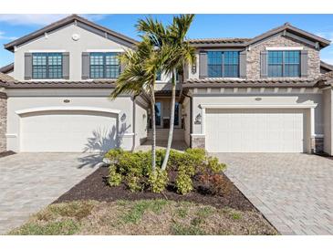 Two-story townhome with attached two-car garage, landscaped front yard, and paver driveway at 17607 Gawthrop Dr # 103, Bradenton, FL 34211