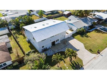 Aerial view of a two-story house with metal roof, driveway, and landscaped yard at 1790 Ezelle Ave, Largo, FL 33770