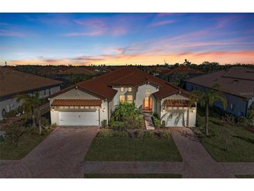 Two-story house with tile roof, two-car garage, and landscaped yard at sunset at 1810 5Th E St, Palmetto, FL 34221
