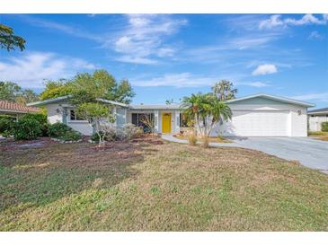 Ranch-style home with a yellow door, white garage, and landscaped yard at 2708 Bigelow Dr, Sarasota, FL 34239