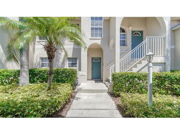 Inviting condo entrance with teal doors, lush landscaping, and a walkway at 4275 Castlebridge Ln # 1312B1, Sarasota, FL 34238