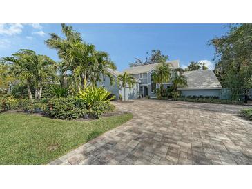 Two-story house with light blue brick exterior, landscaping, and paver driveway at 4892 Peregrine E Pt, Sarasota, FL 34231