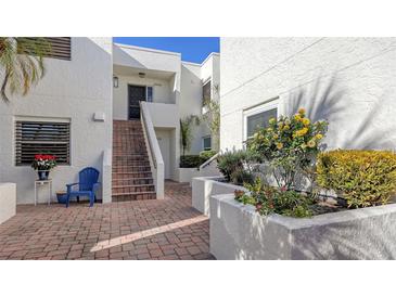 Condo building with courtyard entrance, brick pavers, and lush landscaping at 5152 Marsh Field Ln # 117, Sarasota, FL 34235