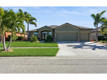 Single-story house with green exterior, three-car garage, and landscaped yard at 318 Star Shell Dr, Apollo Beach, FL 33572