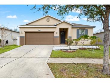 One-story house with brown garage door, gray door, and landscaped yard at 7308 Tangle Bend Dr, Gibsonton, FL 33534