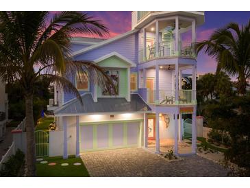 Three-story house with pastel exterior, a two-car garage, and palm trees at 112 Mangrove Ave, Anna Maria, FL 34216