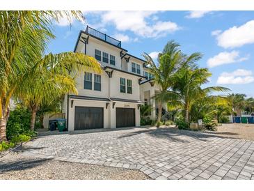 Two-story home with a white exterior, dark gray roof, and a large driveway at 3015 Avenue E, Holmes Beach, FL 34217