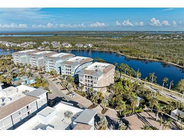 Aerial view of waterfront condo building with parking and landscaping at 395 Aruba Cir # 302, Bradenton, FL 34209