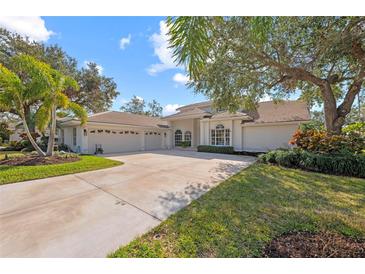 White house with three-car garage, lush landscaping, and a large driveway at 4214 Palacio Dr, Sarasota, FL 34238