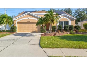 Tan house with solar panels, palm trees, and a well-manicured lawn at 4440 Sanibel Way, Bradenton, FL 34203