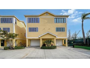 Two-story yellow home with attached garage and landscaping at 653 Cedars Ct, Longboat Key, FL 34228