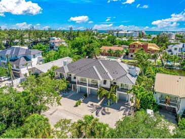 Aerial view of modern home, tropical landscaping, and waterfront location at 6530 Peacock Rd, Sarasota, FL 34242