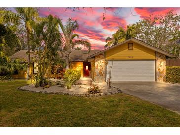 Front view of a yellow house with a stone facade, palm trees, and a landscaped yard at 7612 W 27Th W Ave, Bradenton, FL 34209