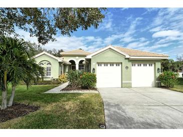 Light green house with two-car garage, landscaping, and a paved driveway at 5097 Faberge Pl, Sarasota, FL 34233
