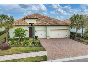 Single-story home with light green exterior, tile roof, and two-car garage at 7036 Whittlebury Trl, Bradenton, FL 34202